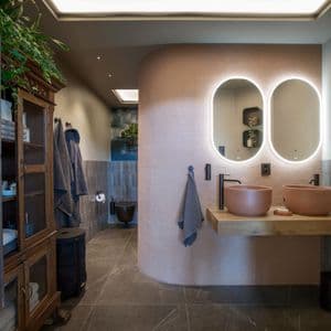 Runde og myke former dominerer på badet; ovale speil, runde bollevasker og runde mosaikkflis på en buet delingsvegg.